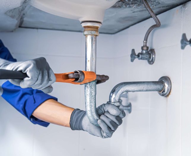 technician-plumber-using-wrench-repair-water-pipe-sink-min